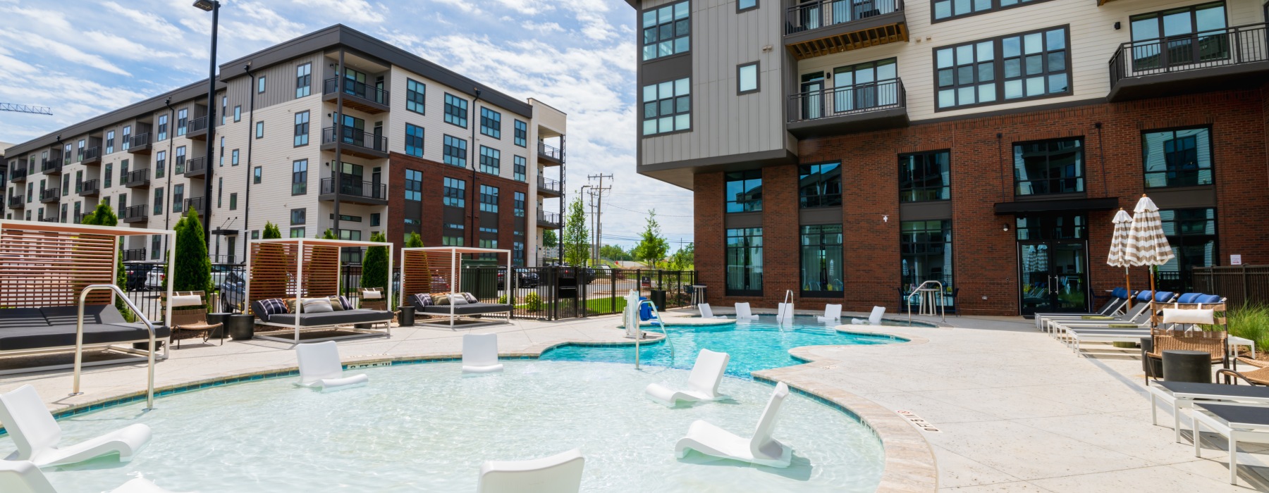 The pool area at 704 at the Quarter Apartments and Townhomes in Charlotte, NC, featuring lounge chairs and umbrellas. The pool area at 704 at the Quarter Apartments and Townhomes in Charlotte, NC, featuring lounge chairs and umbrellas.