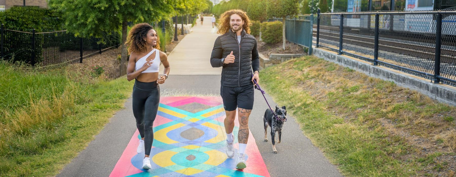 two people walking a dog on a path in a park