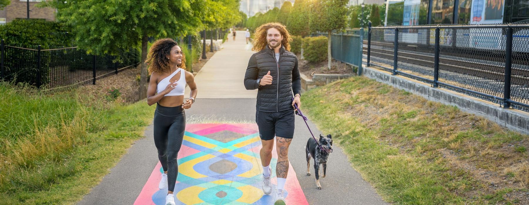 two people walking a dog on a path in a park